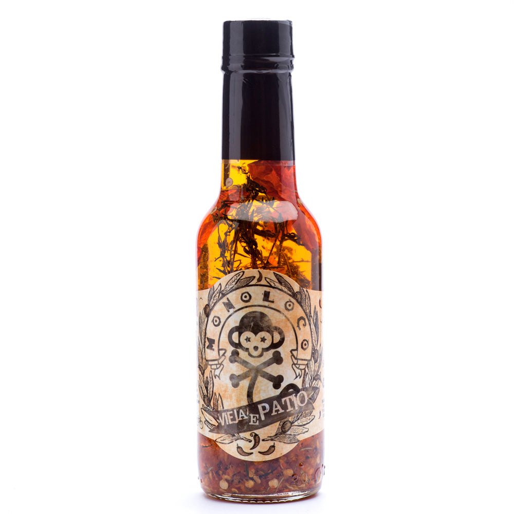 Bottle of MONOLOCO Vieja’e Patio Spicy Olive Oil hot sauce with dried Cayenne peppers and aromatic herbs, 150ml.